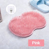 A pink silicone foot scrubber with bristles is shown on a light gray surface.