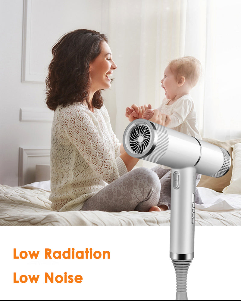 A woman is using a silver infrared blow dryer on a baby in a bright indoor setting.
