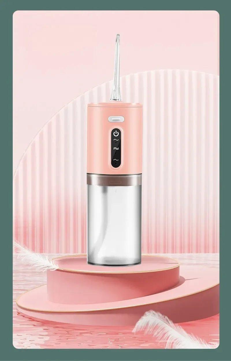 A pink portable electric water flosser with a silver body is displayed on a light pink stand against a striped background.