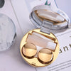 A round marble pattern contact lens storage box with a gold-toned lid and inner compartments.