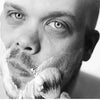 Primer plano en blanco y negro de un hombre afeitándose la barba con un set de cepillo de madera