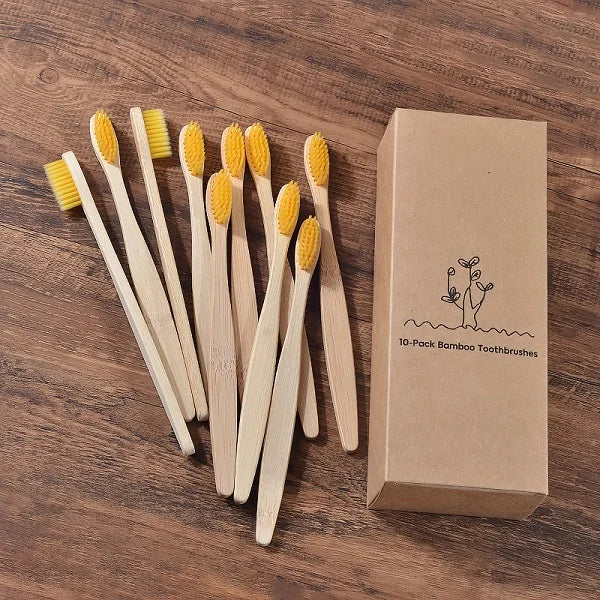 Une boîte en carton contenant un pack de 10 brosses à dents en bambou naturel, posées sur une surface en bois.