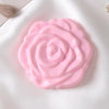 A pink, rose-shaped double-sided pocket makeup mirror resting on a white fabric surface.