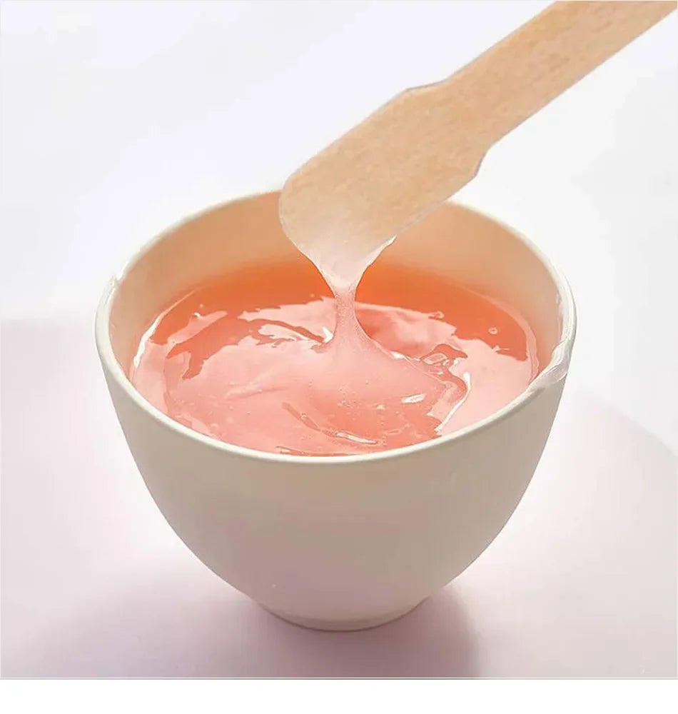 Un bâton en bois est utilisé pour appliquer un produit liquide rose d'un bol pour une épilation naturelle.