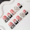 Un set de uñas postizas Y2K con diseños rosa y negro, adornados con cristales y estrellas.