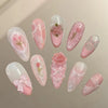 A collection of 24 pink heart pearl press-on fake nails with floral accents displayed on a neutral background.
