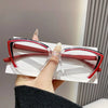 A hand holds a pair of red and white cat eye reading glasses with blue light blocking features.