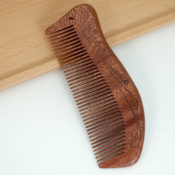 A wooden comb with a curved handle and fine teeth is shown resting on a light wooden surface.