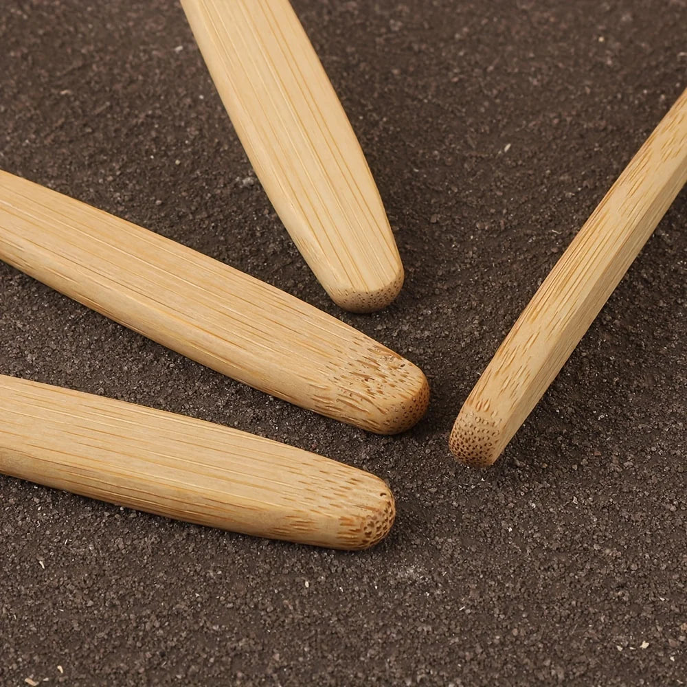 A set of six light-colored bamboo toothbrushes lying on a dark brown surface.