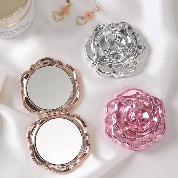A vintage rose design double-sided pocket makeup mirror in pink and silver tones.