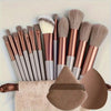 A set of professional makeup brushes in various shades of brown and gray resting on a beige towel.