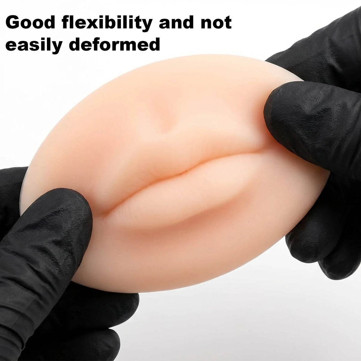 A hand in a black glove holds a smooth, flesh-toned silicone practice skin for tattoo art.