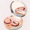 A round marble pattern contact lens storage box with a clear lid revealing pink contact lenses.