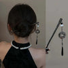 Un vestido negro de cuello alto junto a horquillas para el cabello con borlas de mariposa vintage.