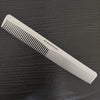 A white anti-static professional hair cutting comb lying diagonally on a dark surface.