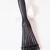A black adjustable detangling hair brush lying on a white surface.