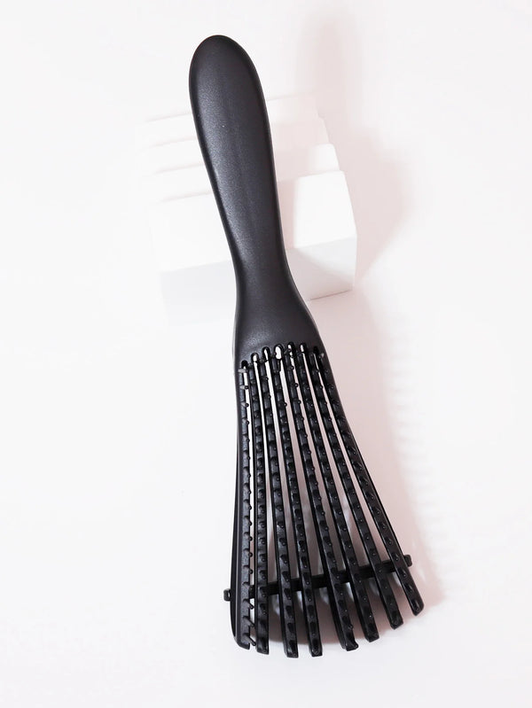 A black adjustable detangling hair brush lying on a white surface.