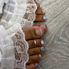 Close-up of a hand with press-on fake nails featuring short square French design and various blue accents