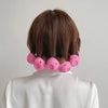 A person's back shows a set of pink silicone heatless curling hair tools placed around the neck.