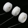 Three white dental floss spools lying on a black surface, with thin strands of floss extending from them.