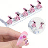 A set of pink magnetic nail art display stands and a pink acrylic nail is shown on a hand.