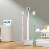 A set of three soft bristle toothbrushes in pink, white, and mint green displayed on a wooden surface.