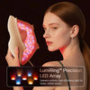 A woman holds a LumiRing Precision LED Array light therapy mask, showing the uniform light output on her face.
