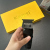 A hand holds a black Kemei electric hair clipper above a yellow box.