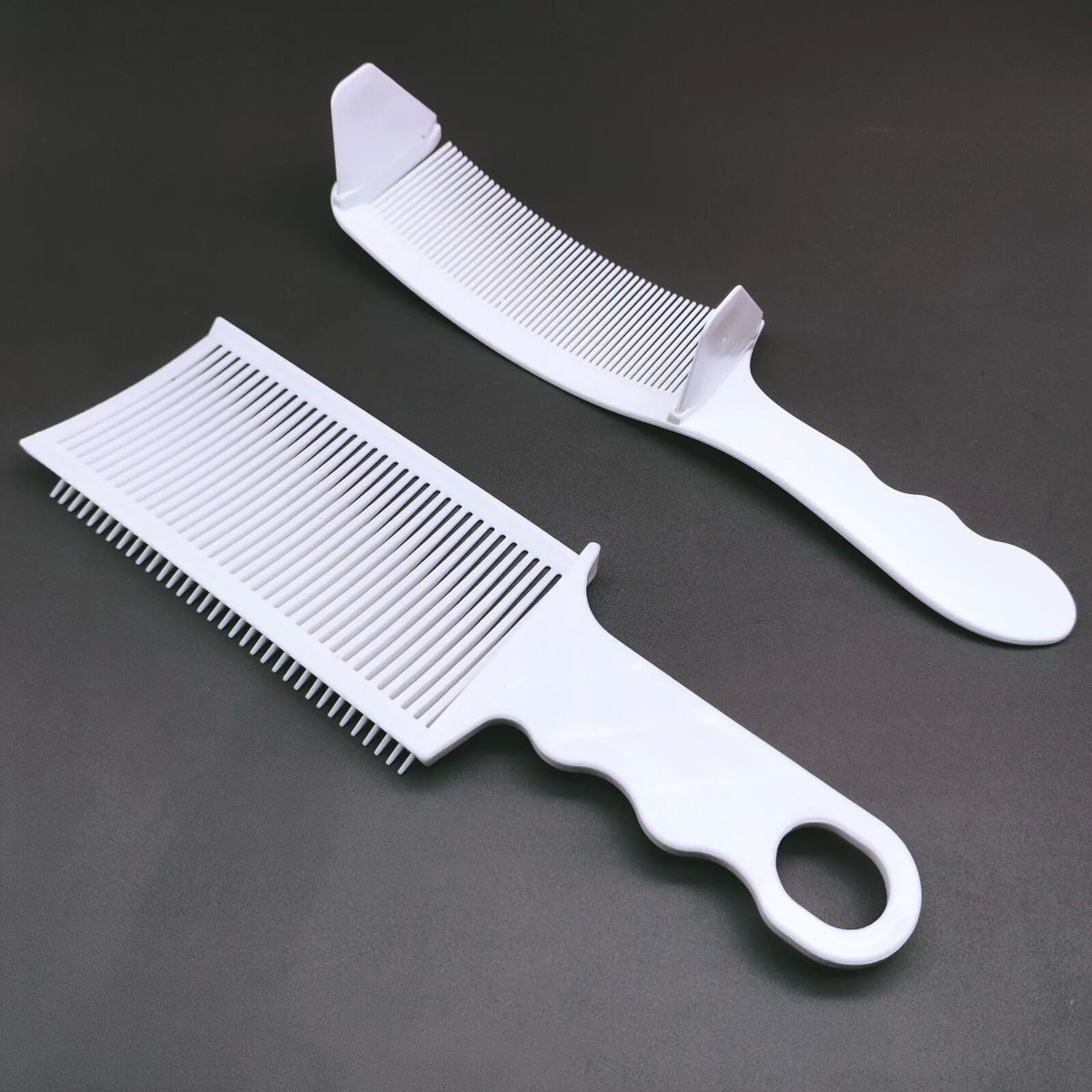 A white professional flat top hair cutting comb set showing a comb and a wider paddle brush on a dark gray background.