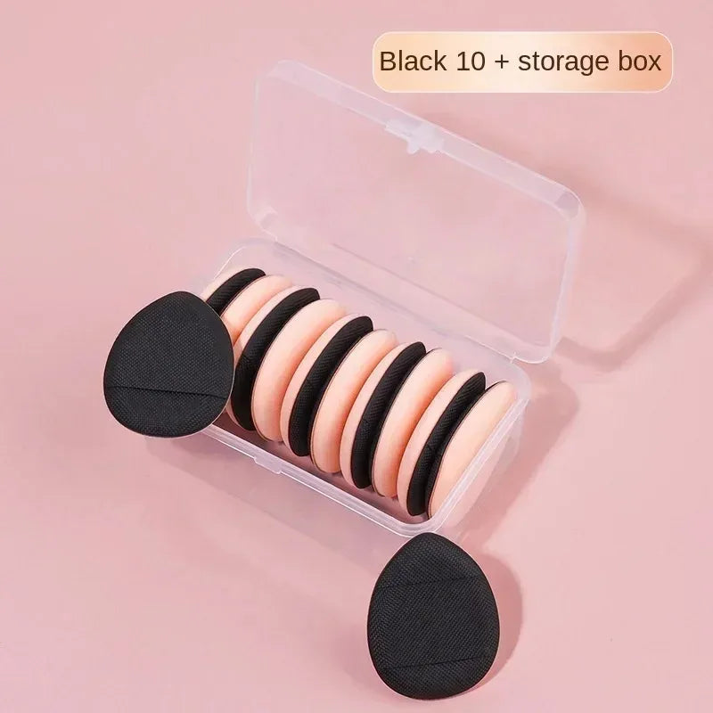 Une boîte de rangement claire contenant dix éponges de fond de teint mini noires et nude pour un maquillage précis.