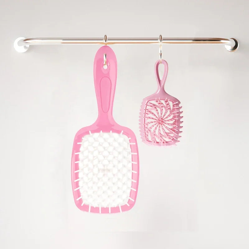 A pink detangling hair comb hanging from a metal bar.