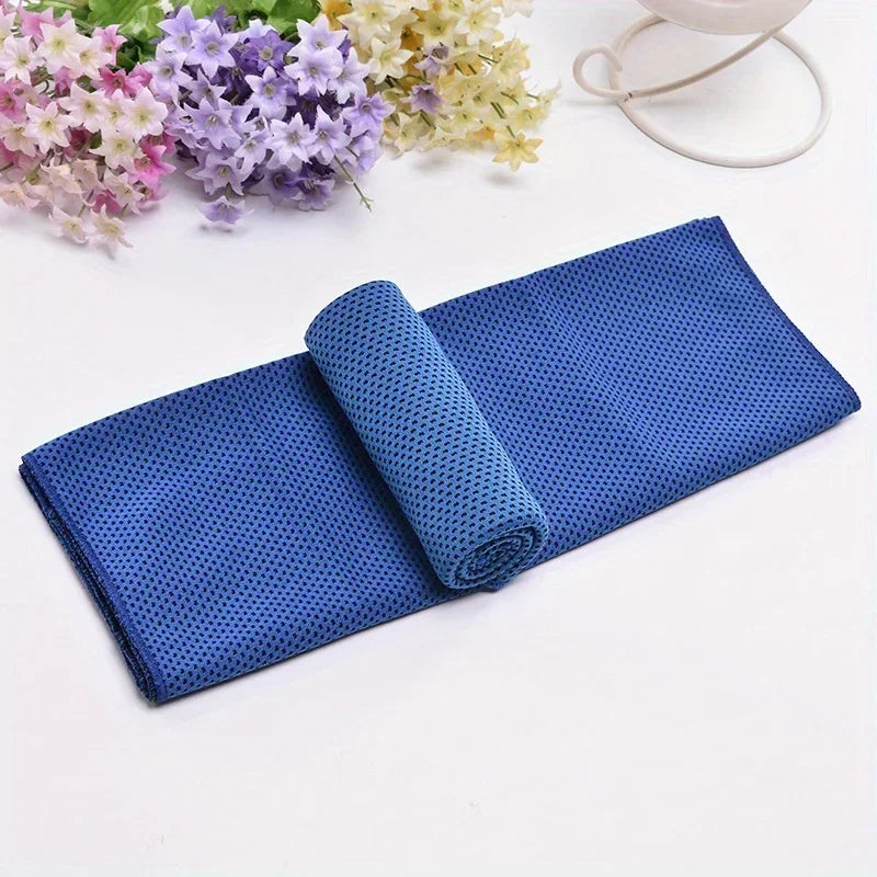 A rolled blue microfiber sport towel next to some light-colored flowers and a white elastic band.