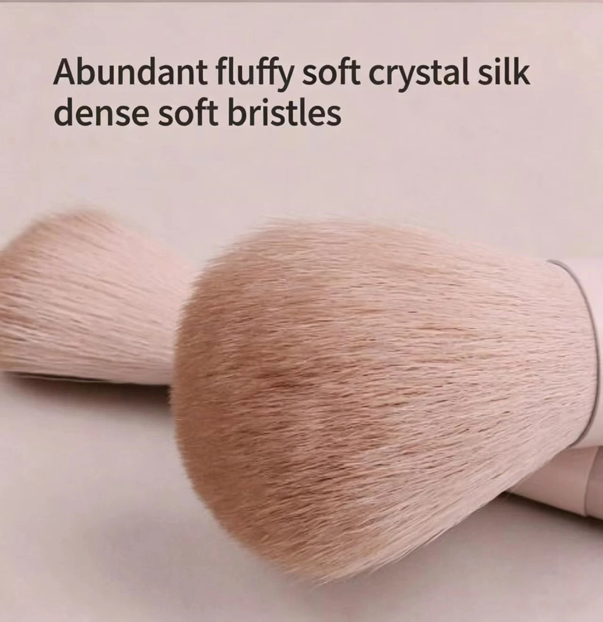 A close-up of a fluffy, light pink crystal silk makeup brush with dense soft bristles.