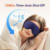 A woman is using a purple electric heated eye mask with a timer set for 15 minutes.