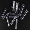 A collection of clear acrylic press-on nails in various lengths and shapes scattered on a dark surface.