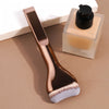 A professional foundation brush with soft nylon bristles resting next to a glass bottle of cosmetic product.