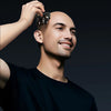 A man is using a seven-blade floating cutting shaver on his head for fast shaving.