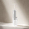 A white electric oral irrigator device with a blue tip is shown standing on a light surface.