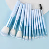 A collection of 14 professional makeup brushes with light blue and white handles and bristles arranged on a light blue backgr