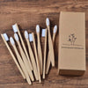 Une boîte en carton contenant dix brosses à dents en bambou posées sur une surface en bois.