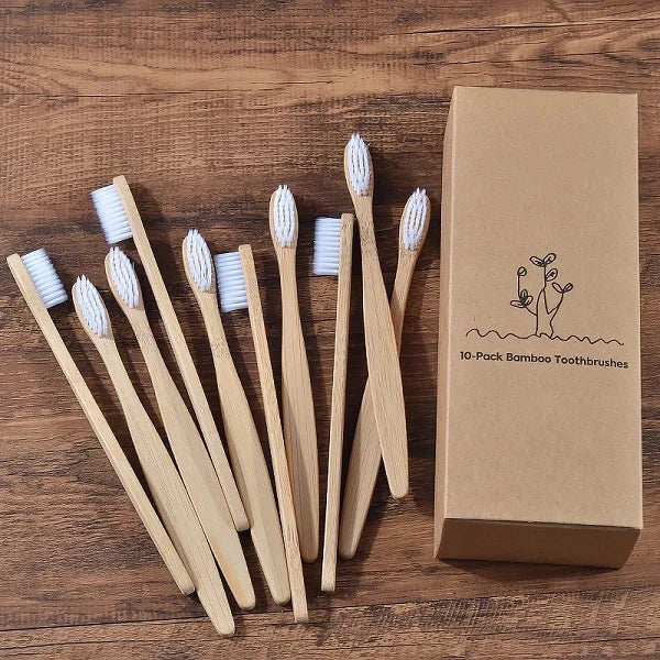Une boîte en carton contenant dix brosses à dents en bambou posées sur une surface en bois.