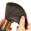 A hand holds a professional hair duster brush with a wood handle and dark bristles against a white background.