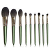 A set of ten professional makeup brushes with green handles displayed against a white background.
