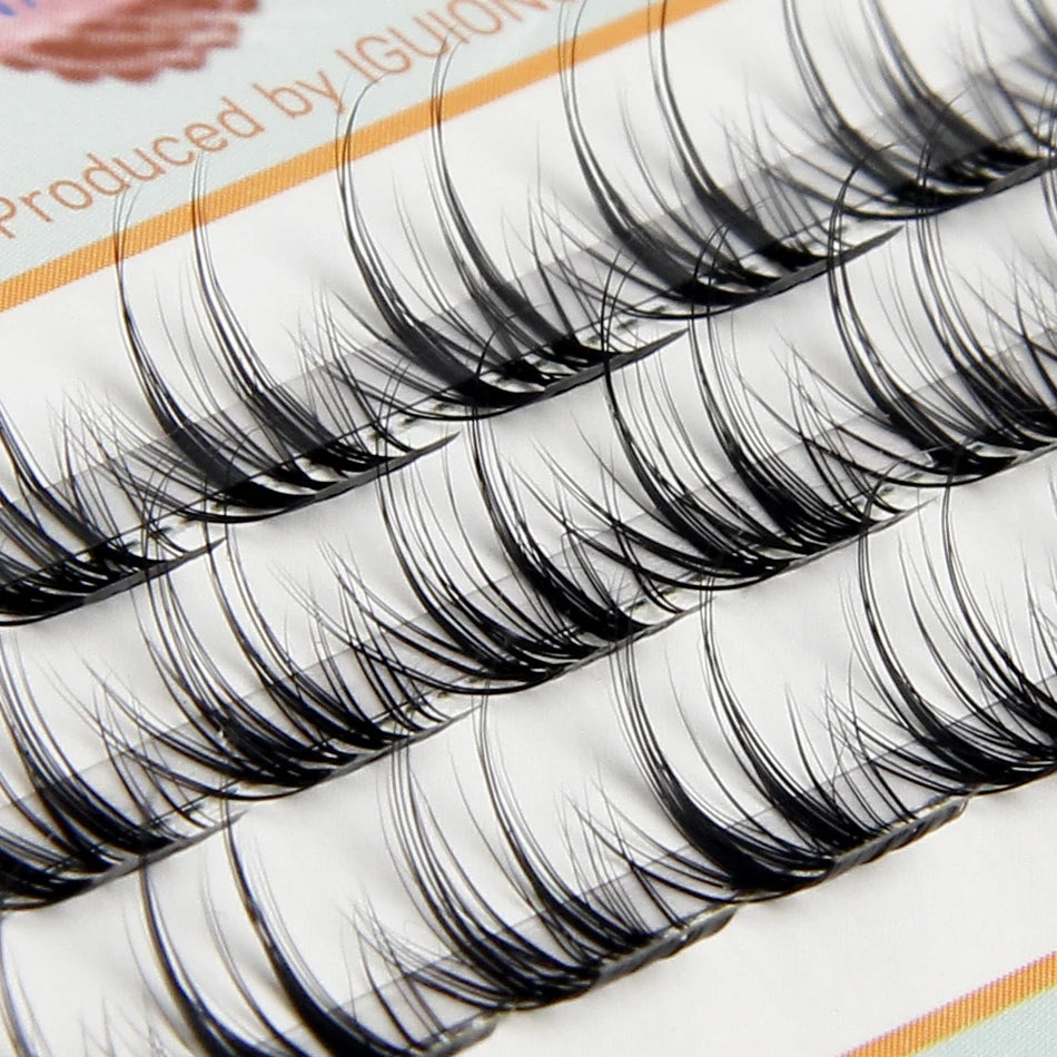 Close-up of natural wispy eyelash extensions in clusters displayed on a white background.