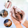 Hands are holding a soft, exfoliating mesh body scrubbing towel with white foam against a light background.