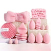 A pink makeup brush set featuring various tools including a bow, sponges, and brushes arranged on a white surface.