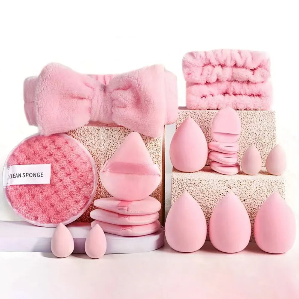 A pink makeup brush set featuring various tools including a bow, sponges, and brushes arranged on a white surface.