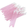 A collection of pink and white crystal lip brushes and lash spoolies arranged in a fan shape.