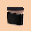 A black precision hand-held foundation makeup brush with light blonde bristles resting in a black holder.