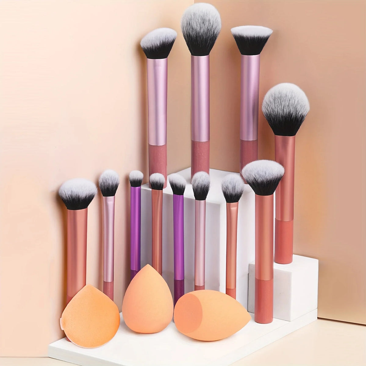 Un set de doce brochas de maquillaje profesionales en varios tonos de rosa y púrpura, exhibidas en un soporte blanco.